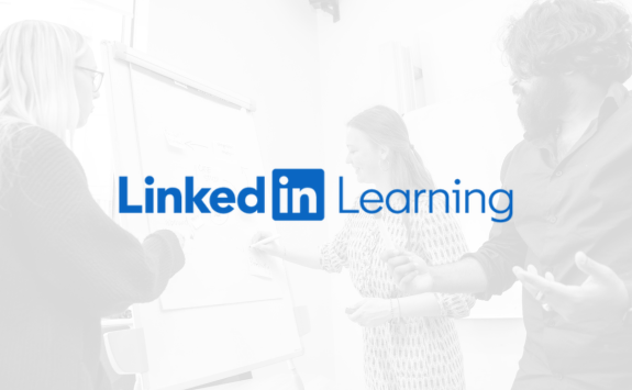 LinkedIn learning logo on a greyscale background with three students writing on a flipchart